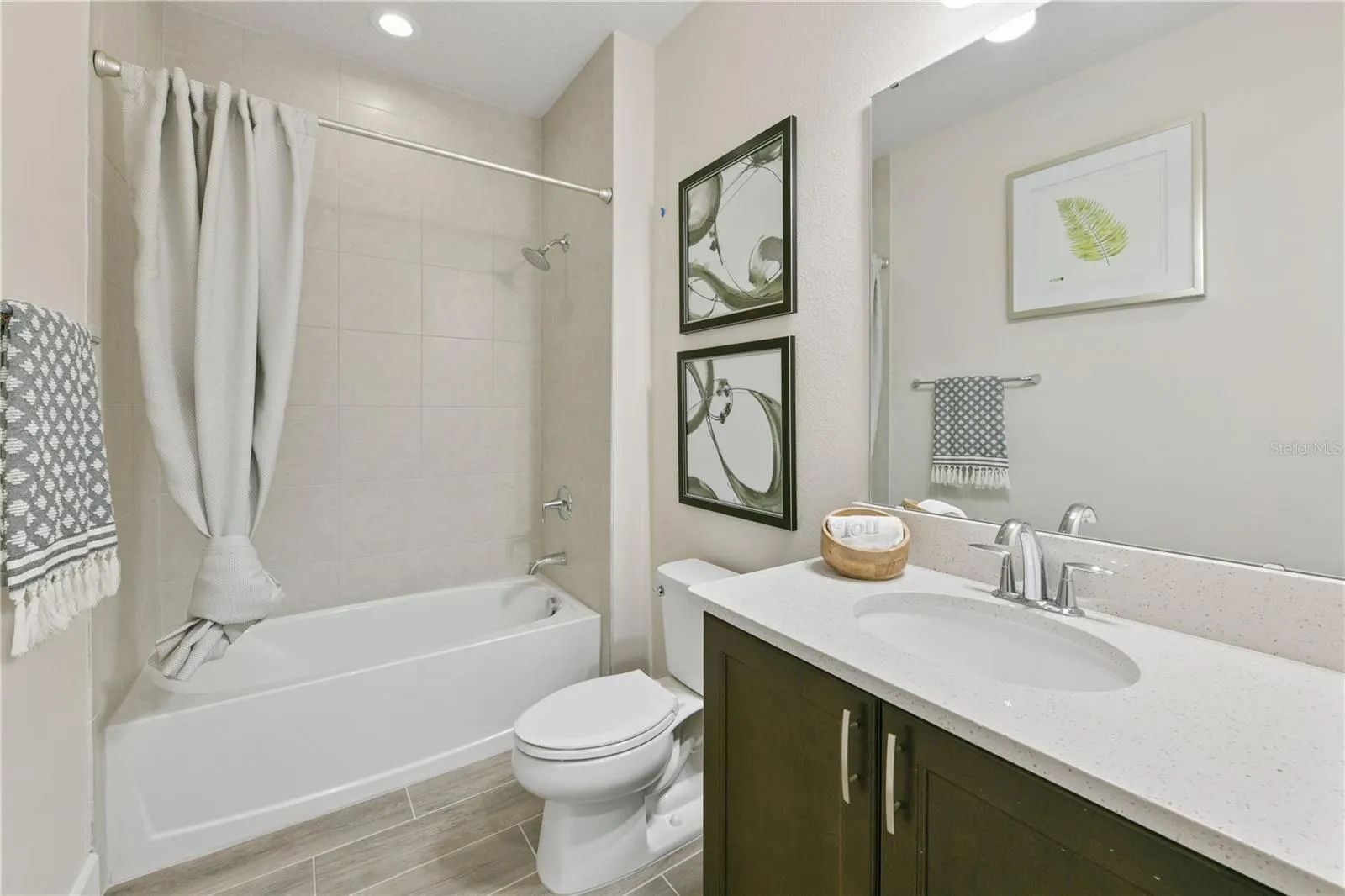 Full bathroom between the two secondary bedrooms at the front of the home highlighted with a tub and quartz vanity
