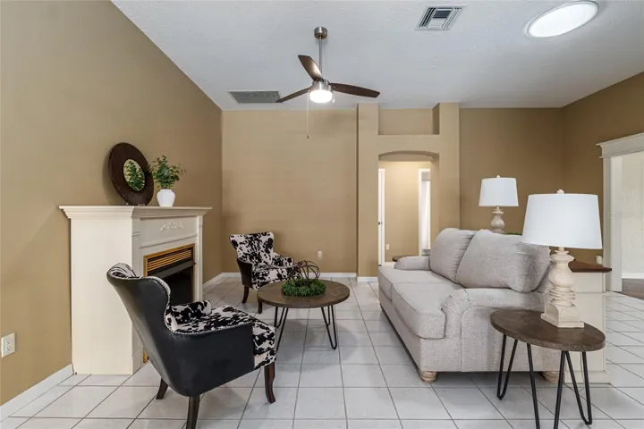 Living Room: Comfortable living area with tile flooring, ceiling fan, and a fireplace that serves as a cozy focal point.