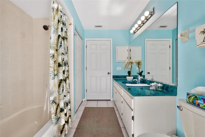 Guest bath has tiled flooring and a combo tub/shower.