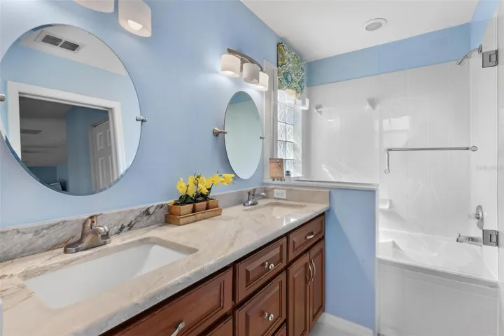 Primary bathroom features dual vanity sinks with tile shower/tub combo.