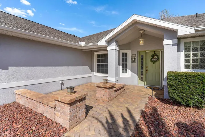 Exterior front entry into home features brick paver patio