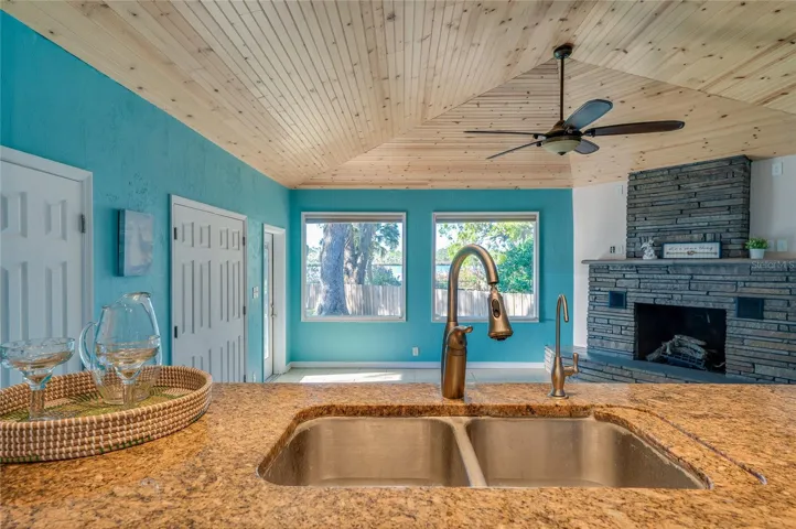 From the kitchen, enjoy views into the adjoining family room with its wood ceiling, fireplace, and large windows. The open arrangement supports a comfortable indoor-outdoor lifestyle.