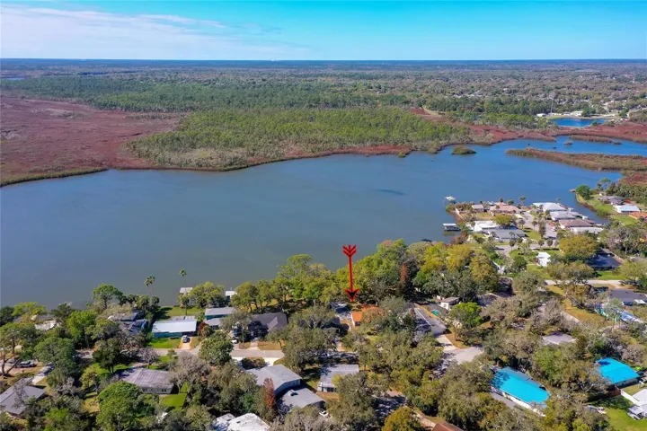 Elevated aerial view highlighting the home’s waterfront position within the surrounding neighborhood and its scenic natural setting.