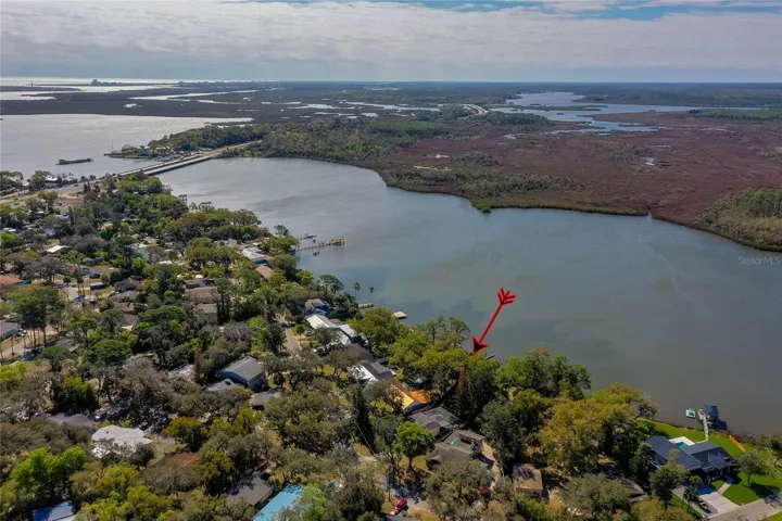 Broad aerial perspective showcasing the property along the shoreline with nearby waterways and surrounding residential streets in view.