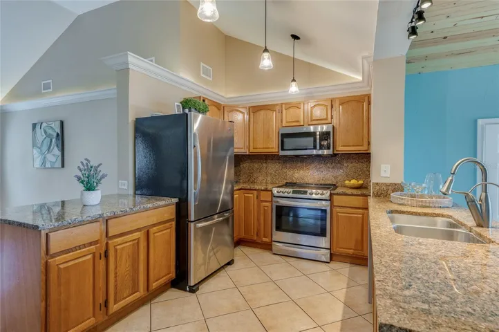 Kitchen with granite countertops, stainless steel appliances, and ample wood cabinetry for storage. The efficient layout makes meal prep and serving easy.