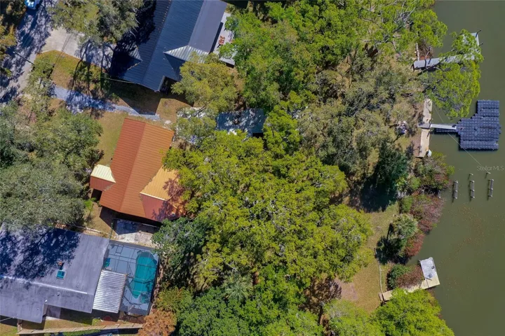 Overhead view highlighting the home’s deep lot extending to the water, with open yard space and a private dock. The expansive layout is easy to appreciate from above.