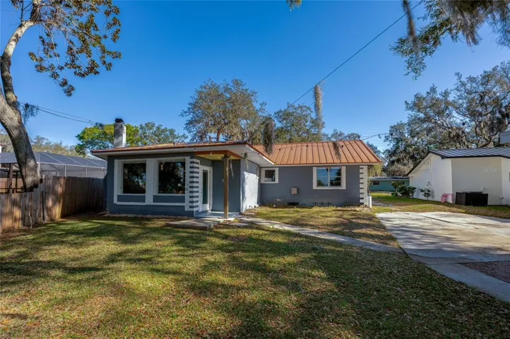 Exterior view showing the home’s metal roof, driveway, and updated exterior finishes. The spacious lot and established trees add to the property’s inviting curb appeal.