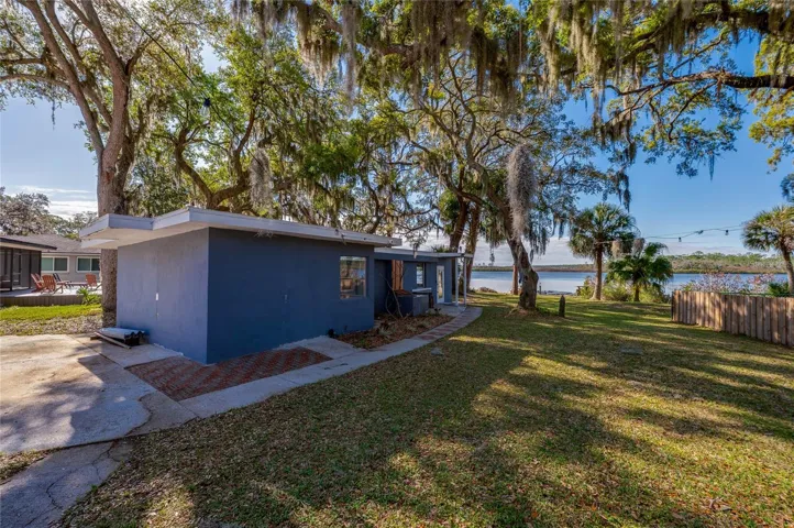 Perspective highlighting the suite’s placement on the spacious waterfront lot. Mature trees provide shade, while the open lawn leads toward the water.