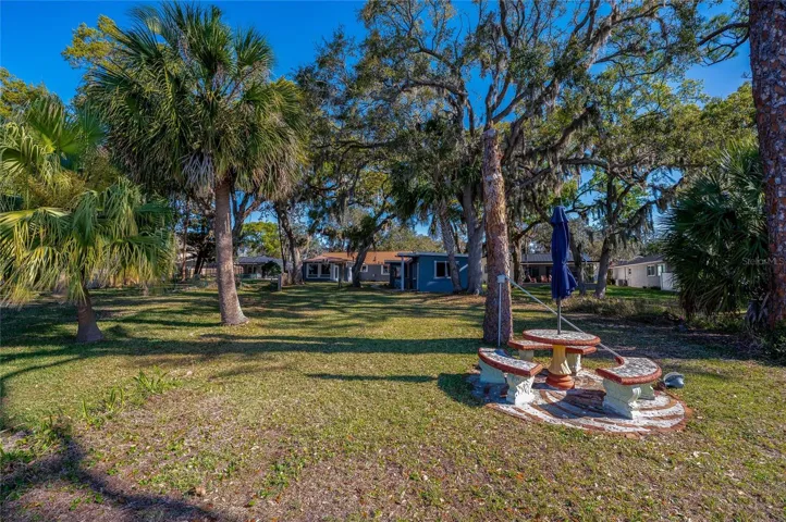 Backyard perspective showcasing the expansive lawn, mature landscaping, and waterfront setting behind the home. The outdoor space offers a peaceful retreat with room to spread out.