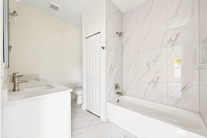 Two additional bedrooms are positioned nearby and share a well-appointed second bathroom with a dual sink vanity, LIGHTED TOUCHSCREEN MIRRORS, custom tiled tub/shower combo, and a convenient linen closet.
