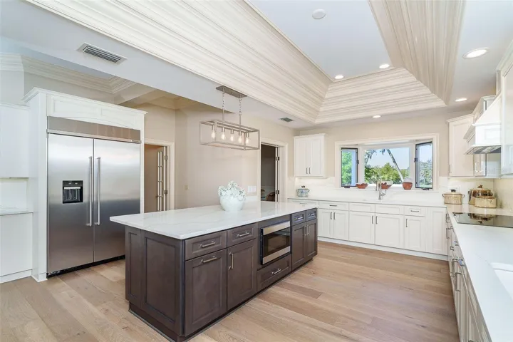 Light-filled kitchen featuring custom cabinetry, quartz countertops, nickel hardware