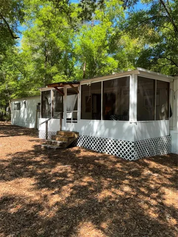The front of the house, with fully screened in porch, enclosing the front door.