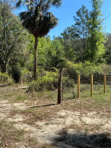 Driveway entrance to property, metal gate with chain and padlock secures the property which is fenced with field fence.