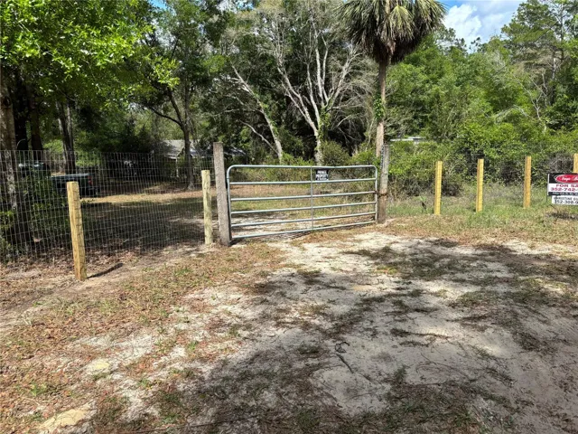 Property entrance gate featuring new field fence on either side.