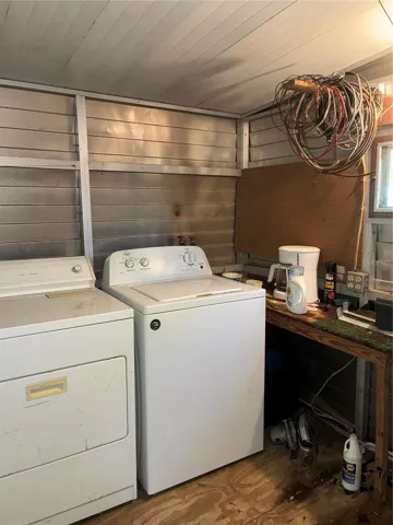 View of inside of rear storage shed showing washer and dryer and work bench.