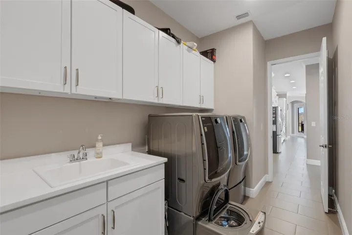 Pedestal Washer and Dryer with Utility Sink and Storage Cabinets. The washer has a large-capacity tub and a lower, smaller tub for delicates and small loads.