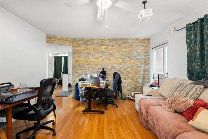 Living room features a decorative accent wall and an open layout that flows into adjacent spaces, offering flexibility for seating, office use, or creative configurations.