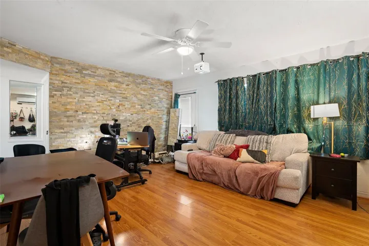 Bright and comfortable living space with multiple windows for natural light, a ceiling fan with light kit, complemented by wood-look laminate flooring and a layout that supports both relaxation and everyday living.