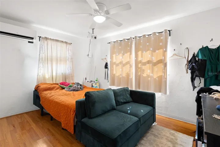 Bedroom 1 is light and bright with multiple windows for natural light, complemented by wood-look flooring, a ceiling fan, and efficient mini-split A/C for year-round comfort.