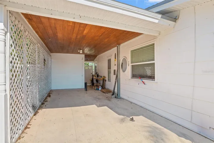 Spacious covered carport with extended driveway provides protected parking and versatile space for storage, projects, or everyday use.