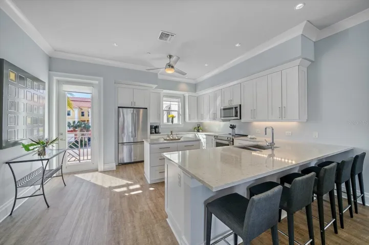 The open-concept kitchen is designed for effortless entertaining, featuring a center island, large breakfast bar, custom cabinetry, Silestone quartz countertops, and KitchenAid stainless steel appliances.