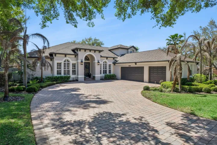 Stunning Mediterranean-style home with arched entry, manicured landscaping, and impressive curb appeal on a quiet circle street