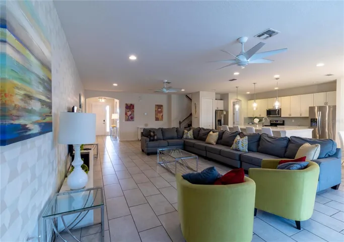 Expansive living area flooded with natural light from large windows overlooking the covered lanai, private pool, and spa. The space features a large smart Tv. Elegant wall decor adds a touch of sofistication.