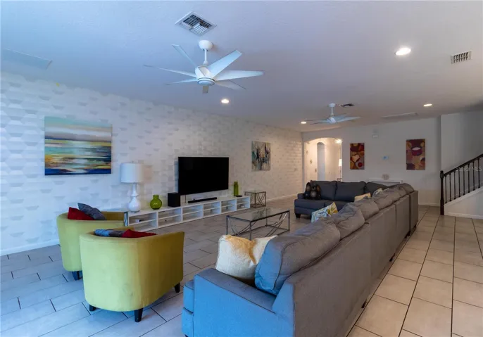 Expansive living area flooded with natural light from large windows overlooking the covered lanai, private pool, and spa. The space features a large smart Tv. Elegant wall decor adds a touch of sofistication.