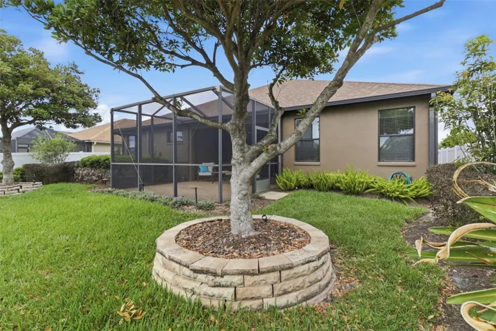 Spacious backyard with mature landscaping and a fully fenced yard, overlooking peaceful waterfront views and the screened lanai—perfect for outdoor living and entertaining.