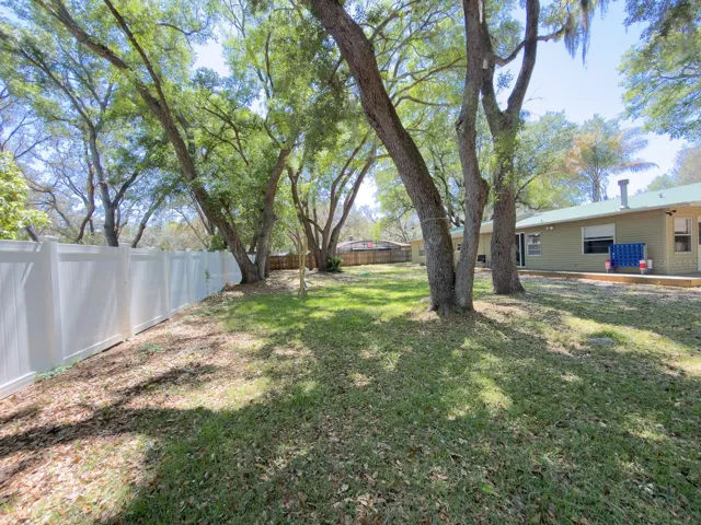 Spacious Backyard Patio. Showing between the trees , the Trellis system for a small garden to grow vegetables. Also, the Zipline for entertaining.