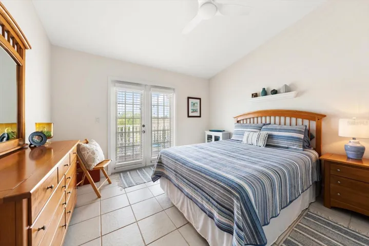 Beautifully illuminated guest bedroom with tall ceilings and access to a shared balcony.