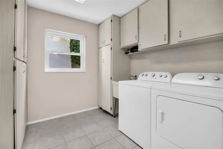 Gracious indoor laundry plus utility sink with abundant cabinetry for storage~