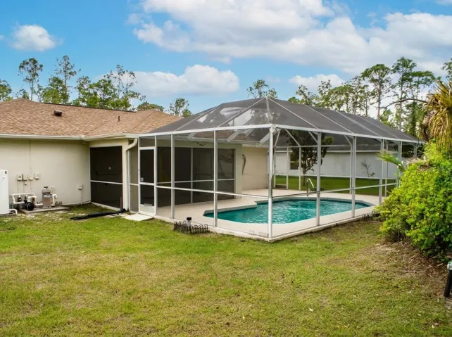Admire the peaceful backyard setting of this oversized North Port corner lot, showcasing mature landscaping, a fully screened pool enclosure, and plenty of green space for outdoor activities.