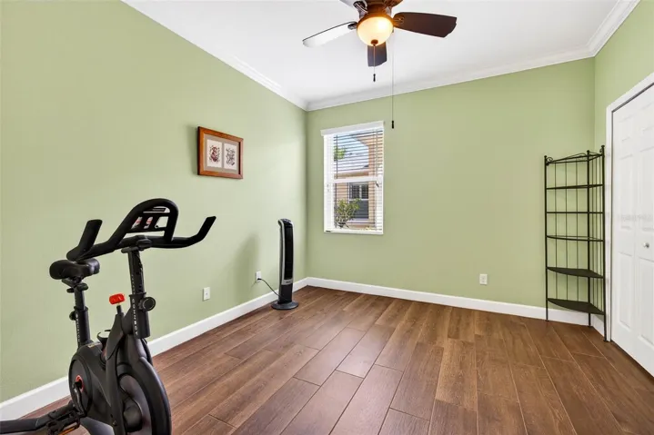 Secondary bedroom with ceiling fan and crown molding.