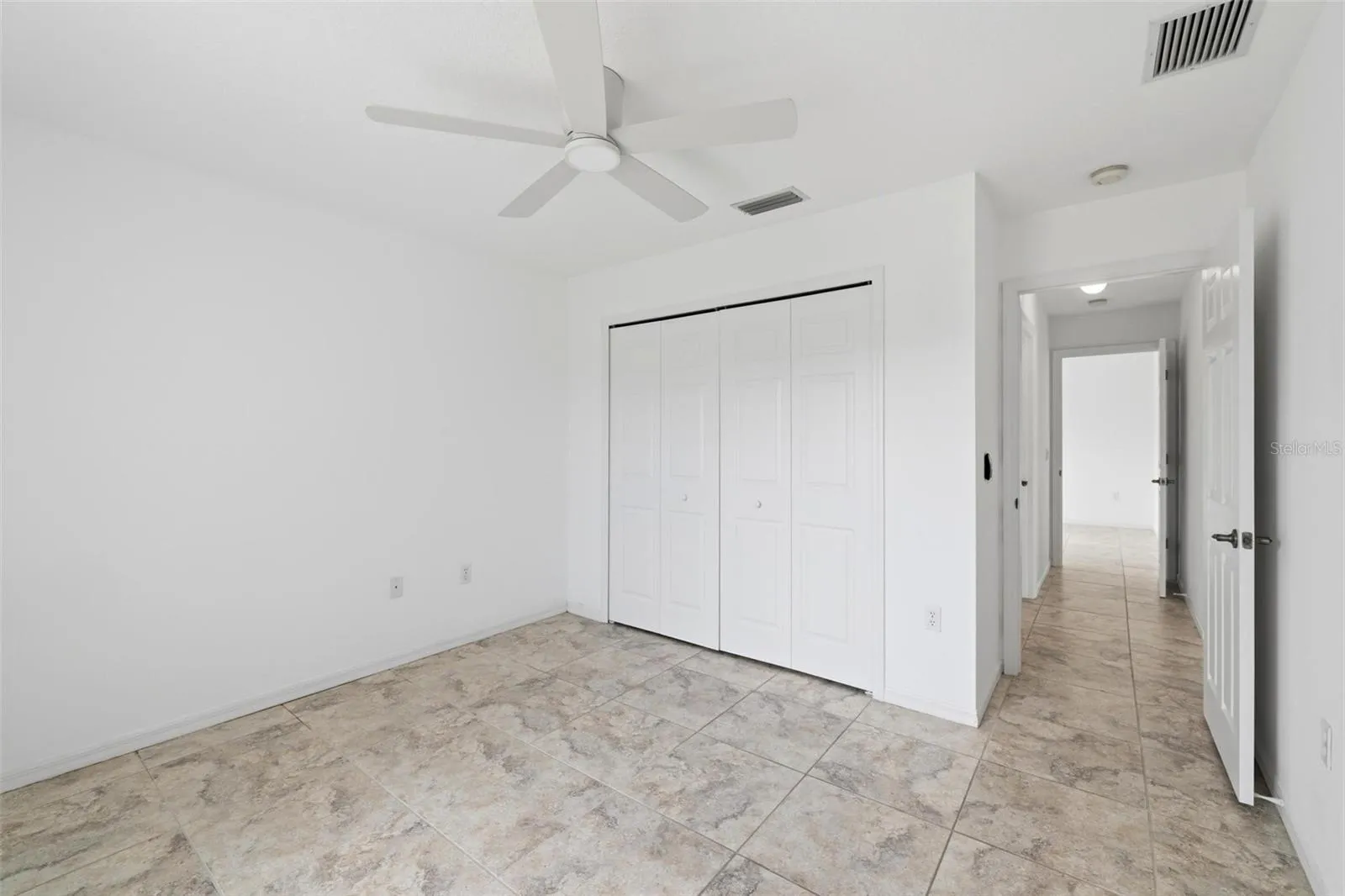 Comfortable bedroom with ceiling fan, neutral walls, and tile flooring throughout
