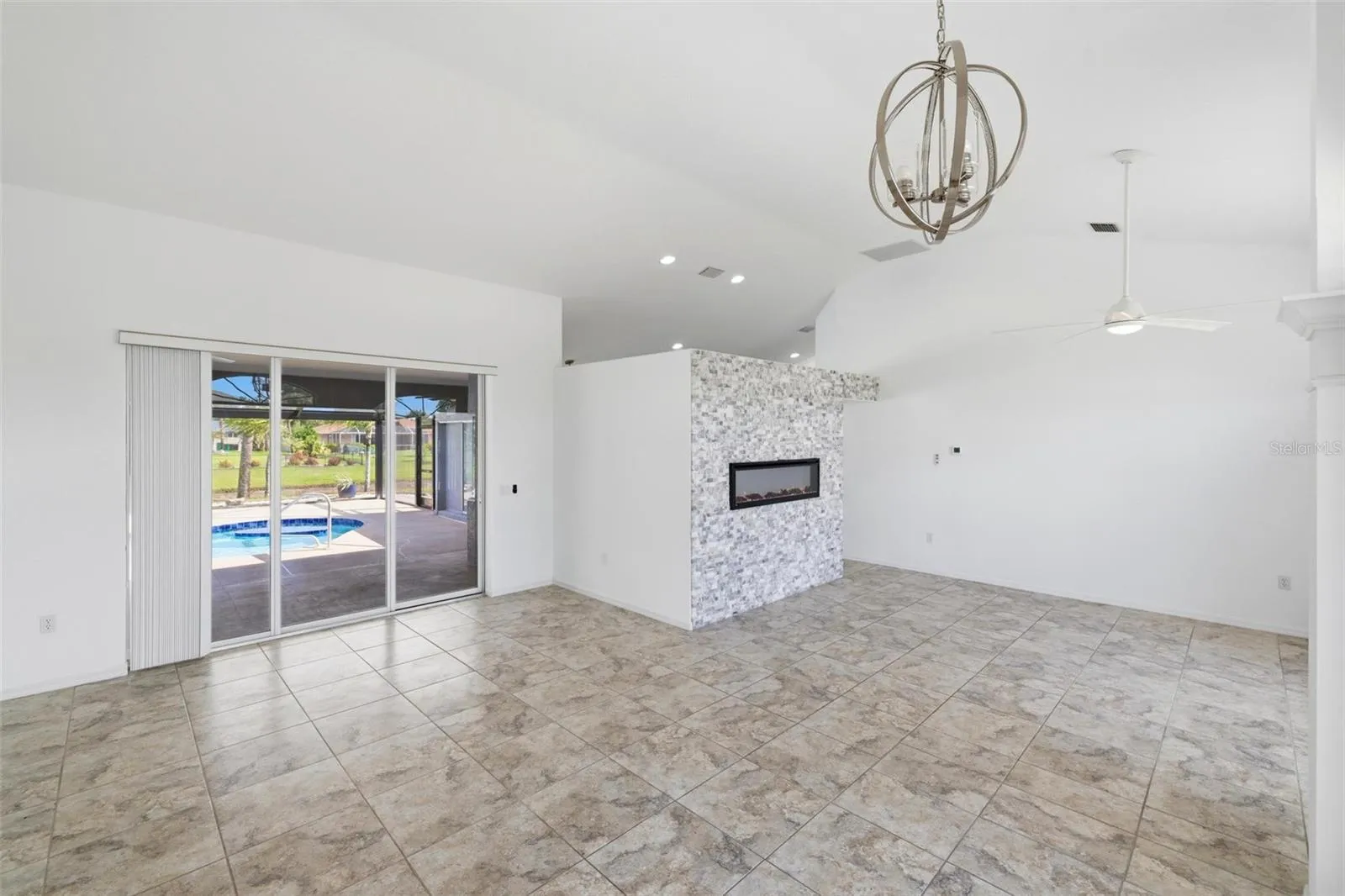 Spacious living area with chandelier, large windows, and light-filled neutral interior
