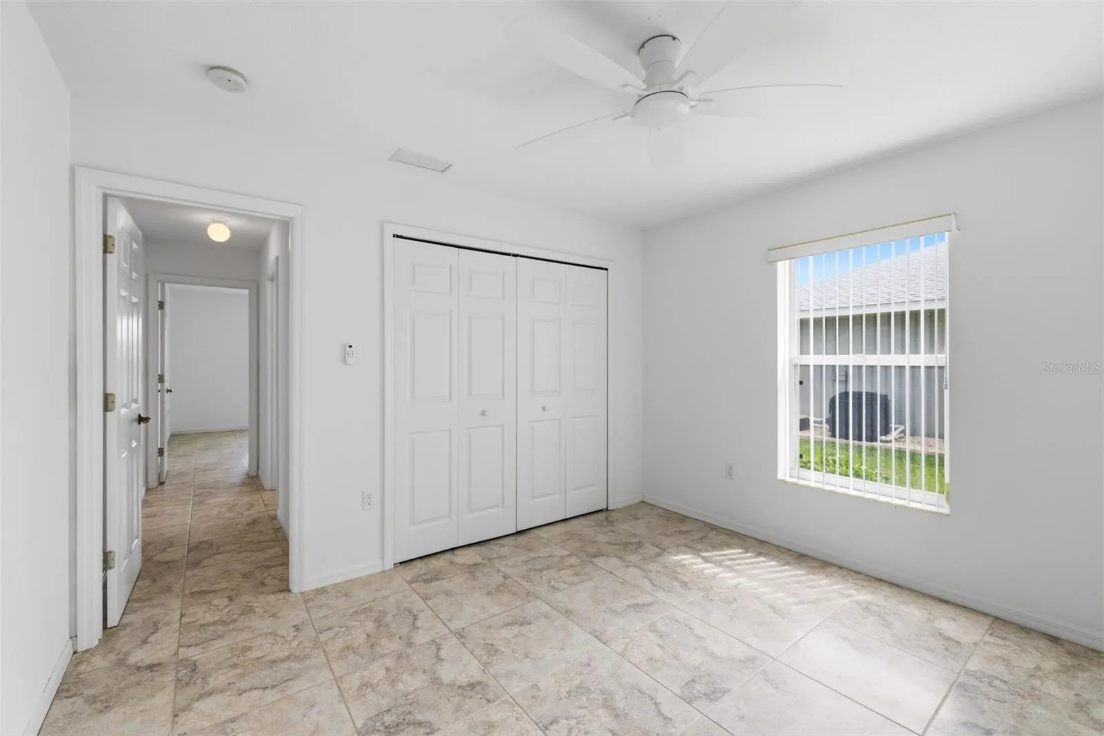 Spacious bedroom with large window, neutral tones, and move-in ready condition