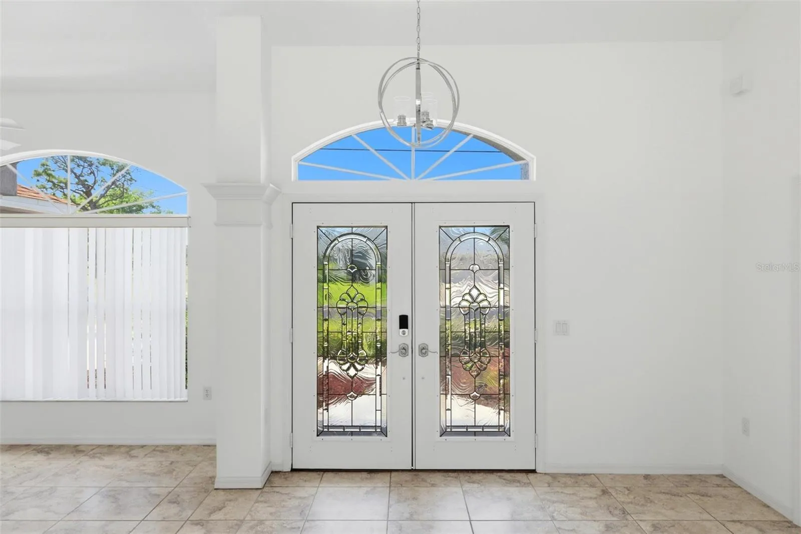 Elegant foyer with arched transom window, double doors, and decorative tile floors
