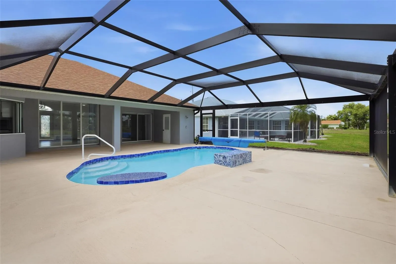 Generous pool deck with panoramic screen enclosure and peaceful backyard setting