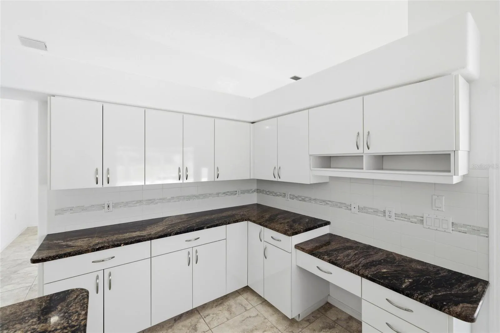 Large kitchen with dark granite countertops, white cabinets, and new 2024 range