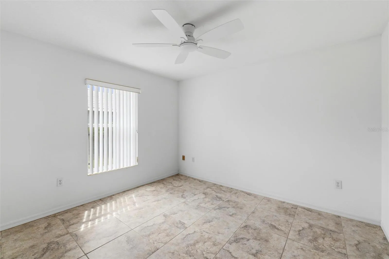 Generously sized bedroom with ceiling fan, neutral paint, and abundant natural light