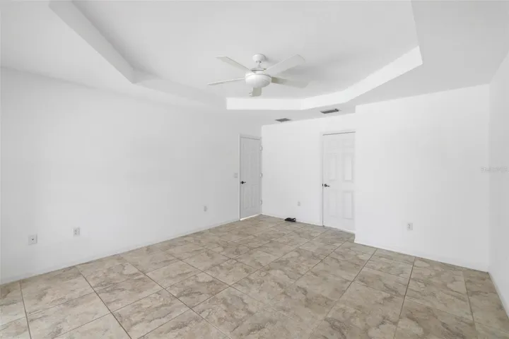 Spacious primary suite with tile floors, ceiling fan, and lots of natural light