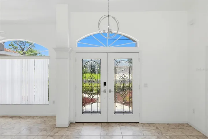 Elegant foyer with arched transom window, double doors, and decorative tile floors