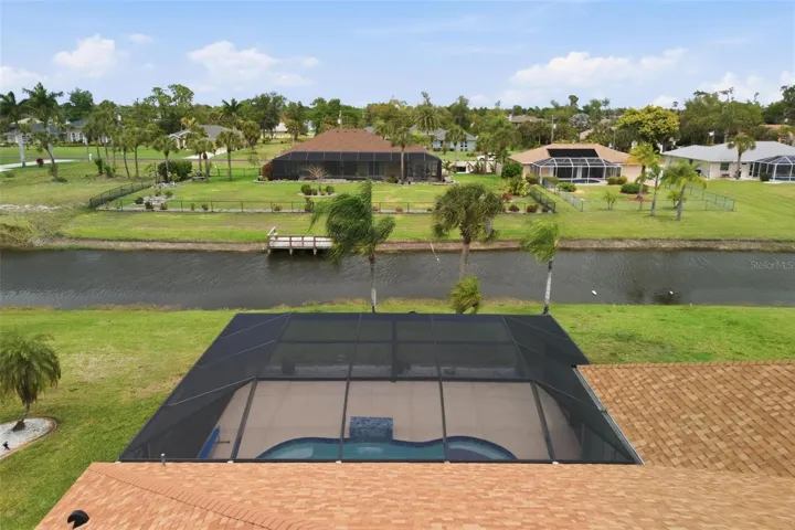 Aerial view highlighting panoramic screen enclosure, owned solar panels (2025), and lush lot