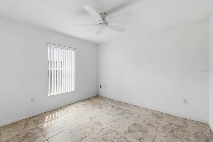 Generously sized bedroom with ceiling fan, neutral paint, and abundant natural light