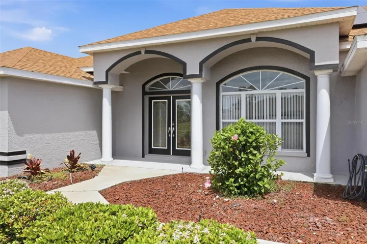 Elegant arched entry with lush tropical landscaping and excellent curb appeal