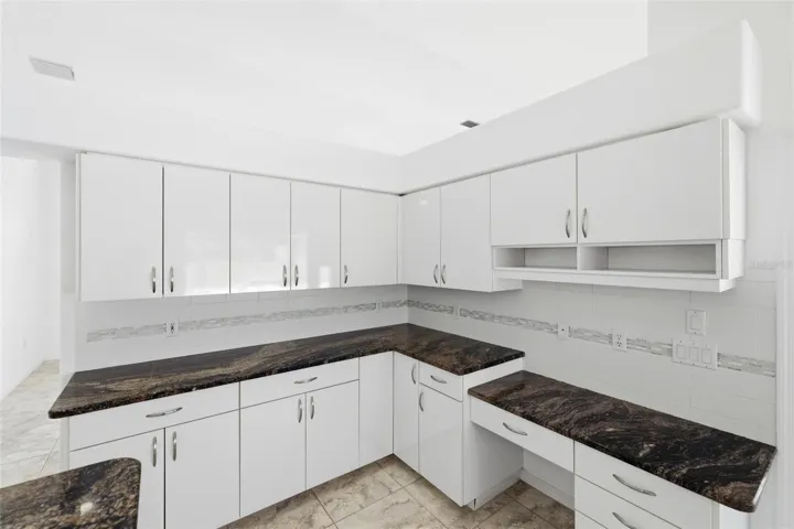 Large kitchen with dark granite countertops, white cabinets, and new 2024 range