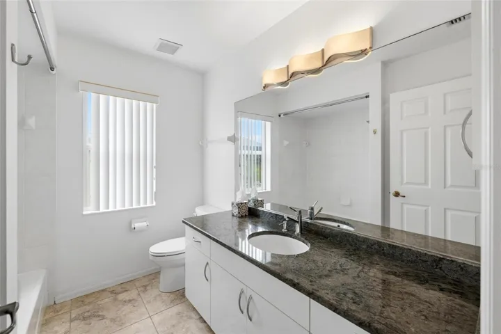 Clean, modern bathroom with dark granite vanity and updated light fixtures