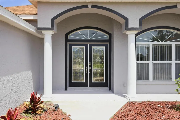 Grand arched double-door entry with decorative glass and covered front porch