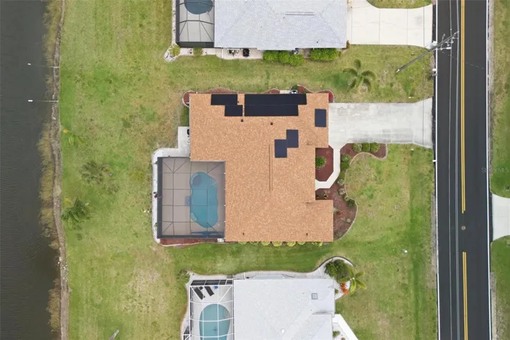 Aerial view showing tile roof (replaced 2023), pool enclosure, and generous lot size